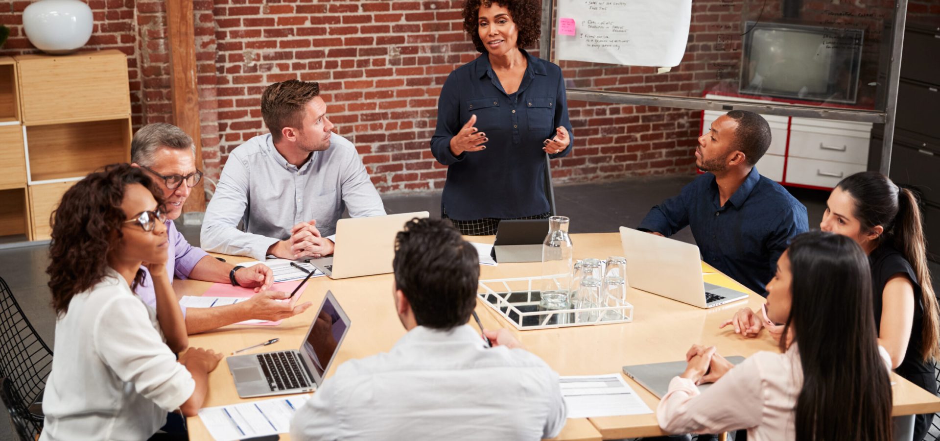 Mature,Businesswoman,Standing,And,Leading,Office,Meeting,Around,Table